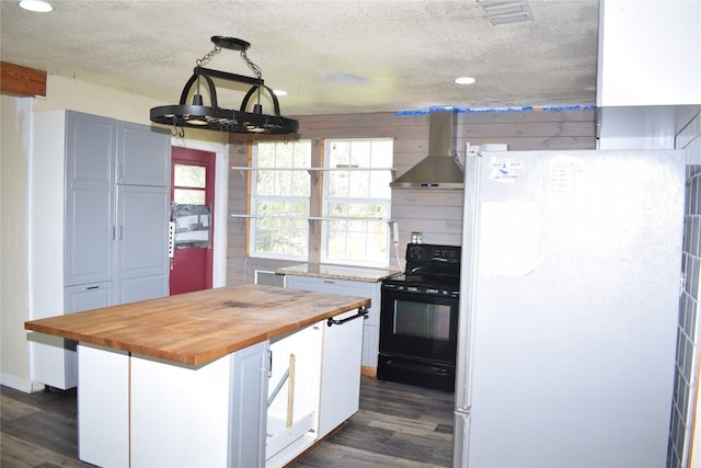 kitchen with wooden counters, wall chimney exhaust hood, decorative light fixtures, white fridge, and black electric range oven