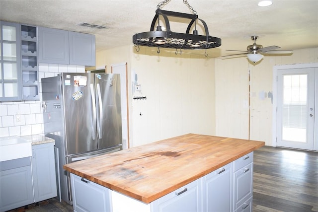 kitchen featuring wood counters, stainless steel fridge, hanging light fixtures, and ceiling fan