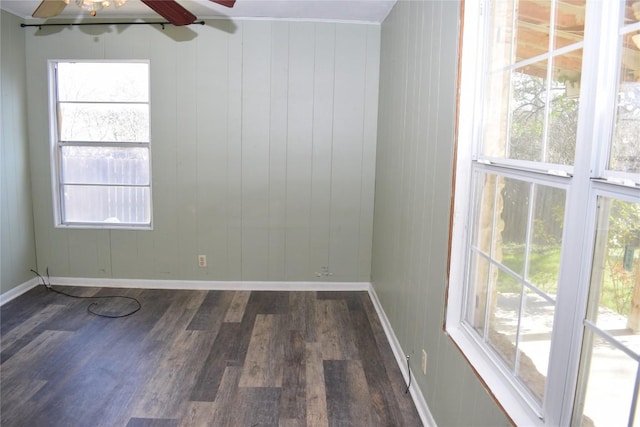 empty room with ceiling fan, a healthy amount of sunlight, and dark hardwood / wood-style flooring