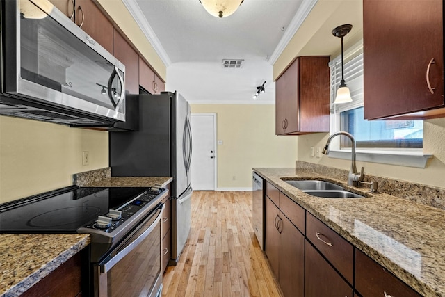 kitchen featuring appliances with stainless steel finishes, light wood-type flooring, crown molding, sink, and pendant lighting