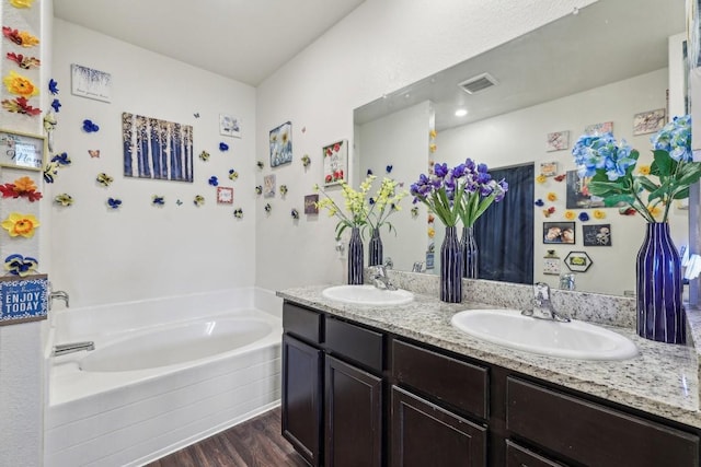 bathroom with tiled tub, hardwood / wood-style flooring, and vanity