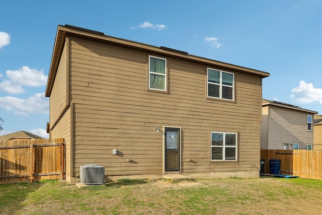 rear view of house featuring central air condition unit and a yard