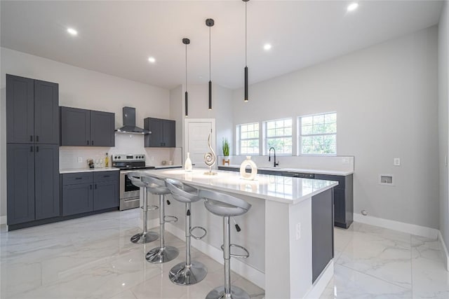 kitchen featuring electric range, wall chimney exhaust hood, decorative light fixtures, a kitchen island with sink, and a breakfast bar