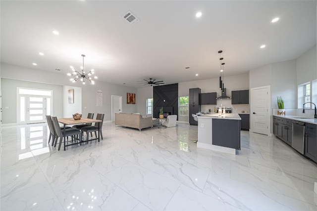 kitchen with pendant lighting, dishwasher, an island with sink, and ceiling fan with notable chandelier