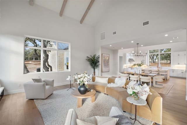 living room with an inviting chandelier, beam ceiling, high vaulted ceiling, and light wood-type flooring