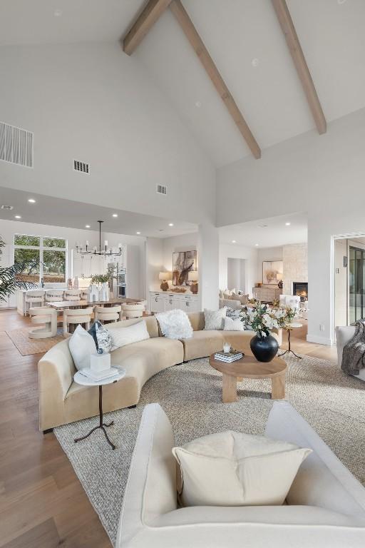 living room with beam ceiling, light hardwood / wood-style flooring, and high vaulted ceiling