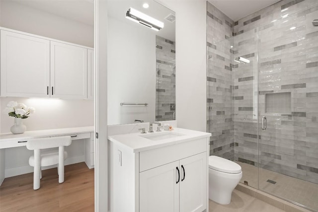 bathroom with a shower with door, vanity, hardwood / wood-style flooring, and toilet