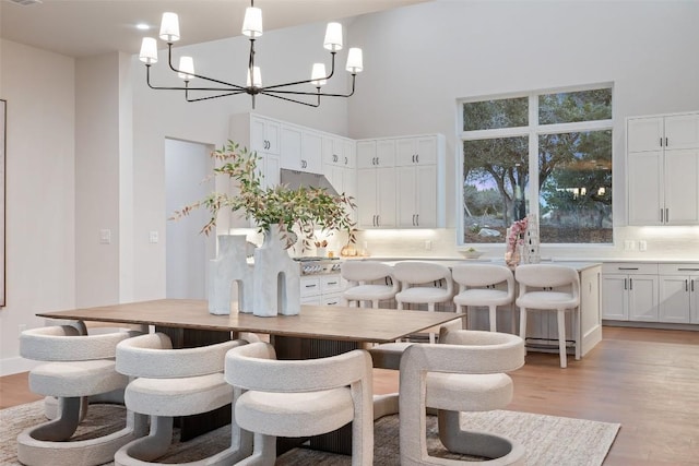 dining space with a high ceiling, a chandelier, and light wood-type flooring