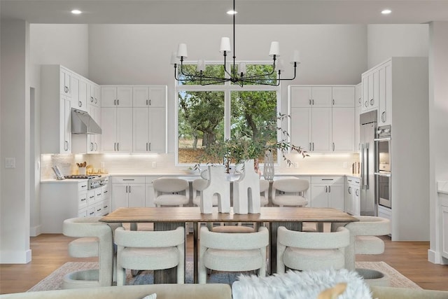 kitchen with white cabinetry, decorative backsplash, light hardwood / wood-style flooring, and a chandelier