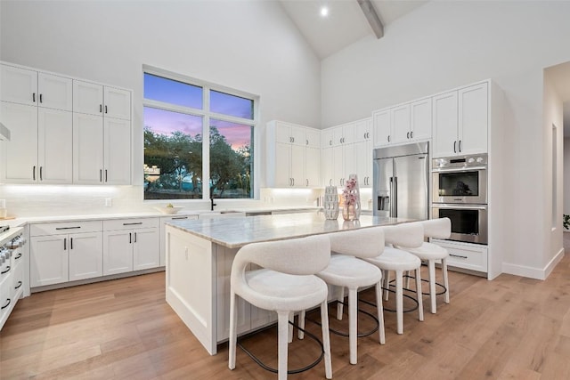 kitchen featuring white cabinetry, a kitchen bar, appliances with stainless steel finishes, and a kitchen island