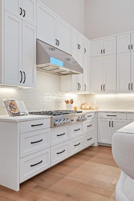 kitchen with white cabinetry, tasteful backsplash, light hardwood / wood-style floors, and stainless steel gas stovetop