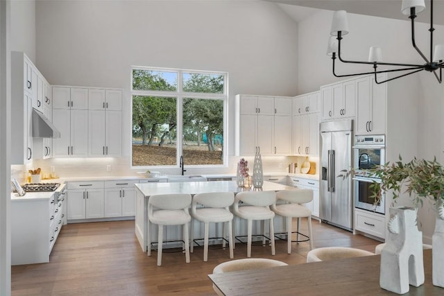 kitchen featuring sink, white cabinetry, built in refrigerator, high vaulted ceiling, and a kitchen island