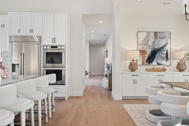 kitchen featuring appliances with stainless steel finishes, light hardwood / wood-style flooring, and white cabinets