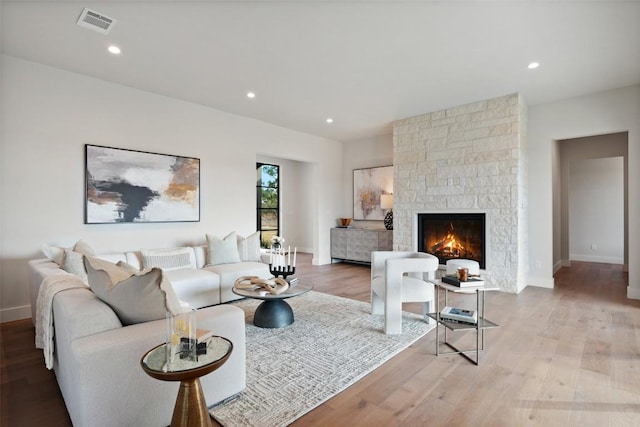 living room with a stone fireplace and light wood-type flooring