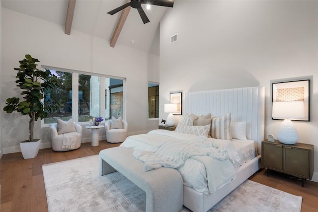 bedroom with ceiling fan, wood-type flooring, high vaulted ceiling, and beamed ceiling