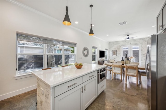 kitchen featuring decorative light fixtures, a center island, plenty of natural light, and appliances with stainless steel finishes