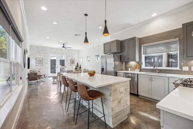 kitchen featuring tasteful backsplash, stainless steel appliances, sink, gray cabinets, and hanging light fixtures