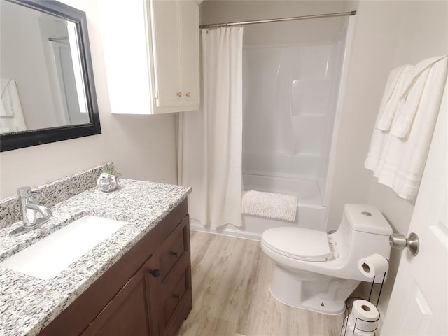 full bathroom featuring hardwood / wood-style flooring, vanity, shower / bath combination with curtain, and toilet