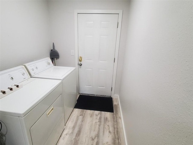 clothes washing area featuring separate washer and dryer and light hardwood / wood-style floors