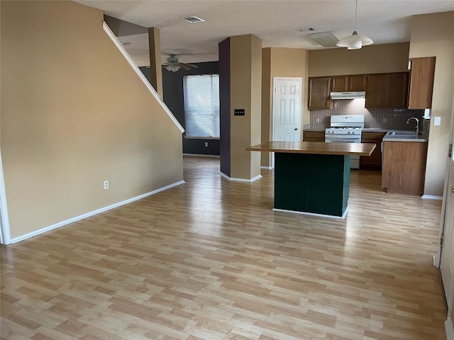 kitchen with decorative backsplash, white gas range oven, ceiling fan, decorative light fixtures, and light hardwood / wood-style floors