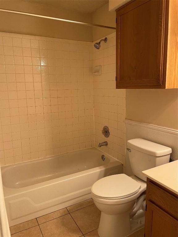 full bathroom with tiled shower / bath, tile patterned flooring, vanity, and toilet