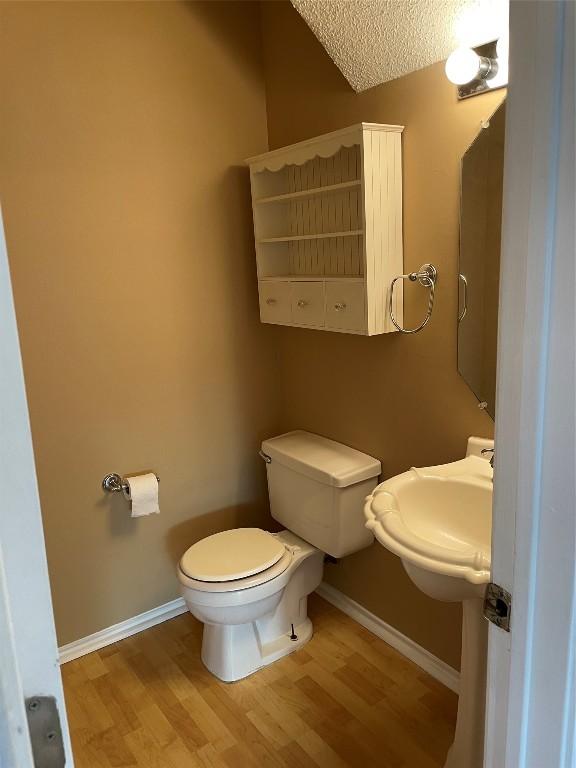 bathroom with hardwood / wood-style floors, a textured ceiling, toilet, and sink