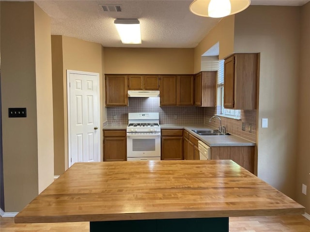 kitchen featuring white appliances, sink, decorative backsplash, a textured ceiling, and butcher block counters