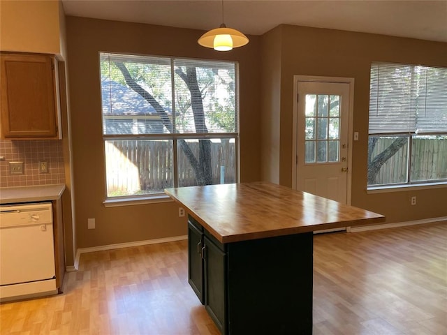 kitchen featuring tasteful backsplash, decorative light fixtures, light hardwood / wood-style flooring, dishwasher, and a kitchen island