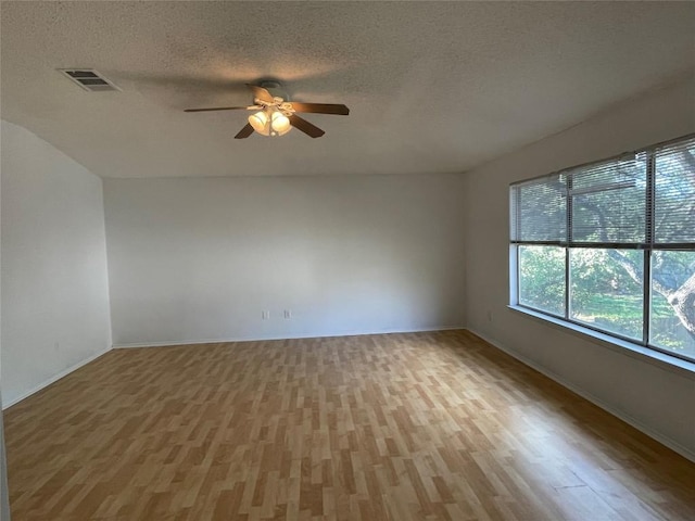 spare room with ceiling fan, light hardwood / wood-style floors, and a textured ceiling