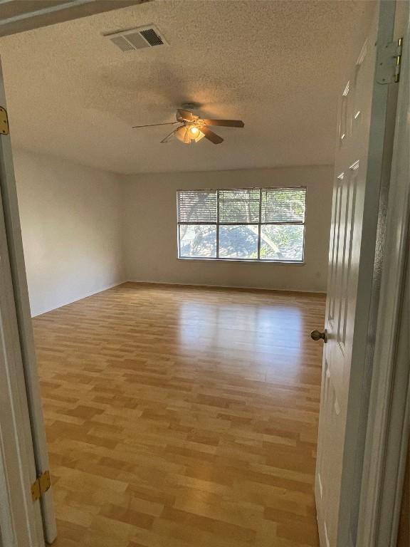 unfurnished room featuring a textured ceiling, light wood-type flooring, and ceiling fan