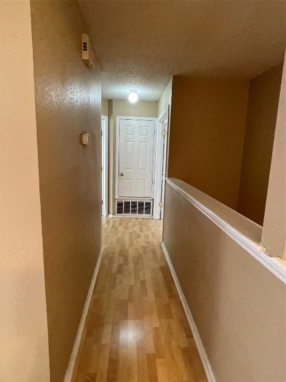 hall featuring a textured ceiling and light wood-type flooring