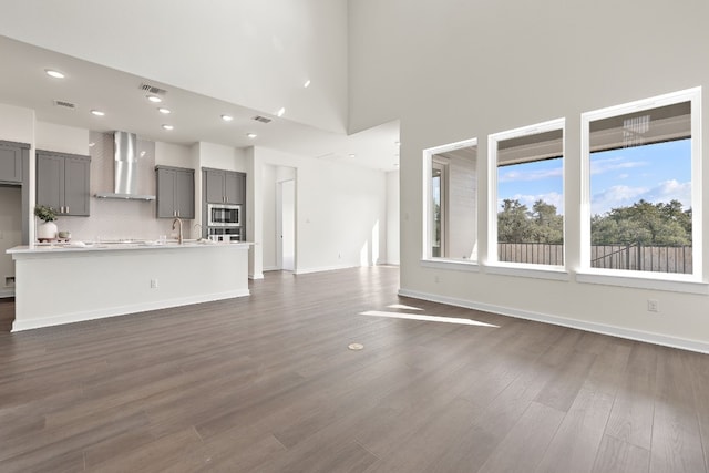 unfurnished living room featuring dark hardwood / wood-style flooring, a towering ceiling, and sink