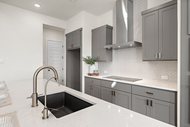 kitchen featuring gray cabinetry, black electric stovetop, sink, wall chimney exhaust hood, and light stone countertops