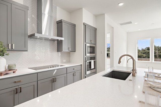 kitchen with light stone countertops, gray cabinetry, black electric cooktop, wall chimney range hood, and oven