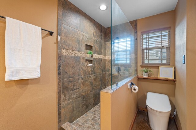 bathroom featuring toilet and a tile shower