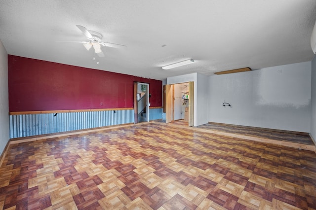 empty room with ceiling fan, parquet flooring, and a textured ceiling