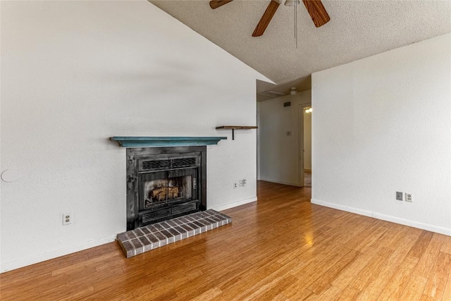 unfurnished living room featuring vaulted ceiling, ceiling fan, a fireplace, a textured ceiling, and wood-type flooring