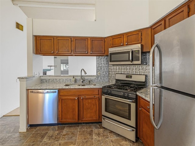 kitchen with light stone countertops, sink, a towering ceiling, and stainless steel appliances