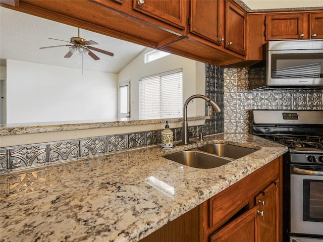 kitchen featuring light stone countertops, sink, tasteful backsplash, vaulted ceiling, and appliances with stainless steel finishes