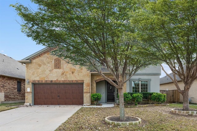 view of front of property featuring stone siding, an attached garage, concrete driveway, and fence