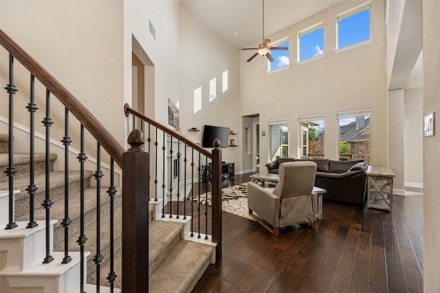 living room featuring visible vents, dark wood-style floors, stairway, baseboards, and ceiling fan