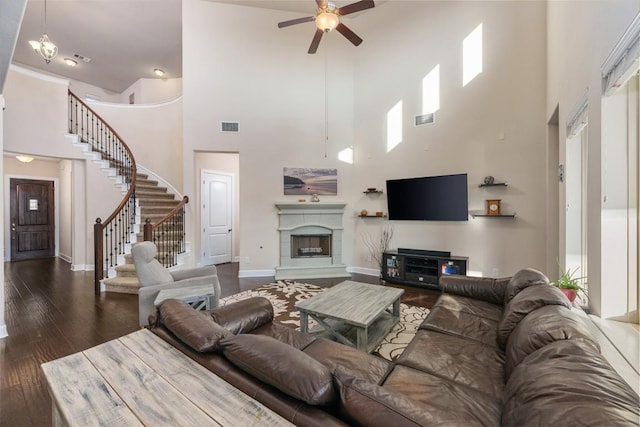 living room featuring ceiling fan with notable chandelier, dark hardwood / wood-style flooring, and a high ceiling