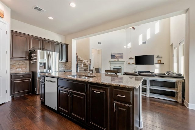 2715 Mariposa Way, Round Rock, TX 78665 - kitchen with appliances with stainless steel finishes, tasteful backsplash, light stone countertops, dark brown cabinets, and recessed lighting