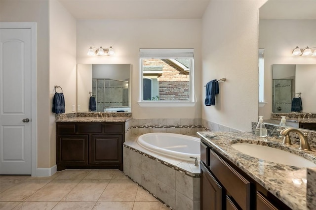 full bath featuring tile patterned flooring, a shower stall, two vanities, a bath, and a sink