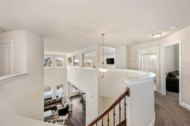 hallway featuring visible vents, an upstairs landing, a notable chandelier, carpet floors, and baseboards