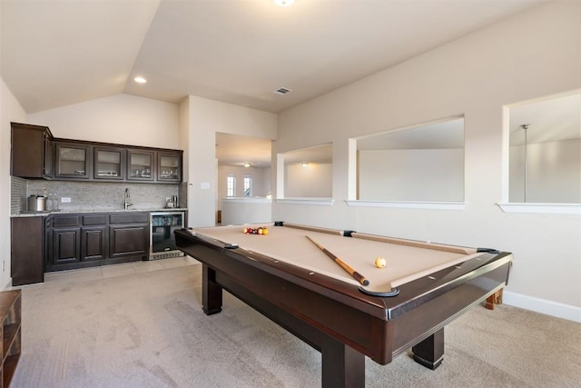 recreation room featuring wine cooler, light colored carpet, lofted ceiling, wet bar, and a sink