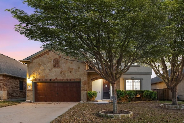 view of front of home featuring stone siding, an attached garage, and concrete driveway