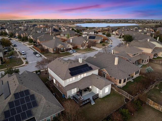 aerial view at dusk with a residential view and a water view