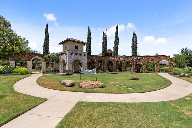 view of front of home featuring stucco siding, stone siding, and a front lawn