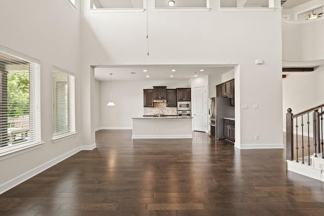 2715 Mariposa Way, Round Rock, TX 78665 - unfurnished living room with a towering ceiling, dark wood-style floors, stairway, and recessed lighting